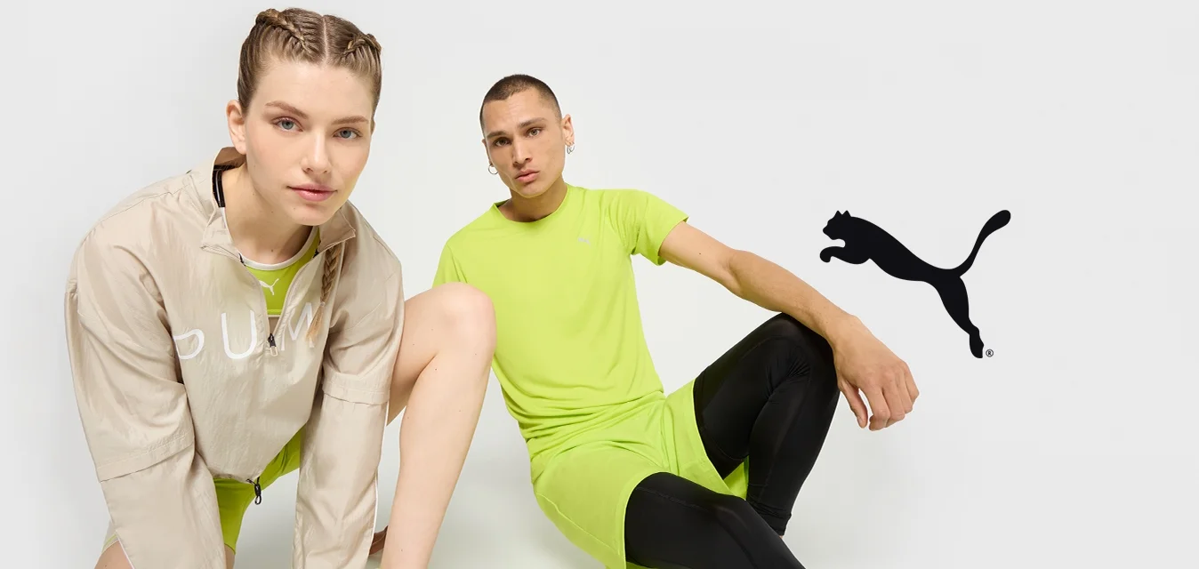 Abbigliamento PUMA: giacca leggera beige con logo, due individui in abbigliamento sportivo verde brillante, leggings neri, vestibilità moderna, dettagli minimi.