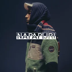 Persona di profilo che indossa una giacca di pile verde e nera, un cappello bianco e una sciarpa blu con strisce rosse e bianche su uno sfondo scuro.