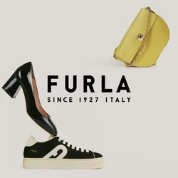 Scarpa con tacco alto in pelle verniciata nera in equilibrio su una borsa gialla, accanto a una sneaker casual bianca e nera su sfondo bianco semplice.