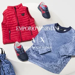Gilet trapuntato rosso, felpa blu con logo stampato, borsa con coulisse abbinata e sneaker per bambini in blu navy e rosso su una piattaforma bianca.
