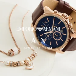 Orologio con cinturino in pelle marrone, quadrante blu e dettagli in oro rosa; orologio con cinturino in rete argentata e quadrante impreziosito da cristalli; delicate collane in oro rosa.