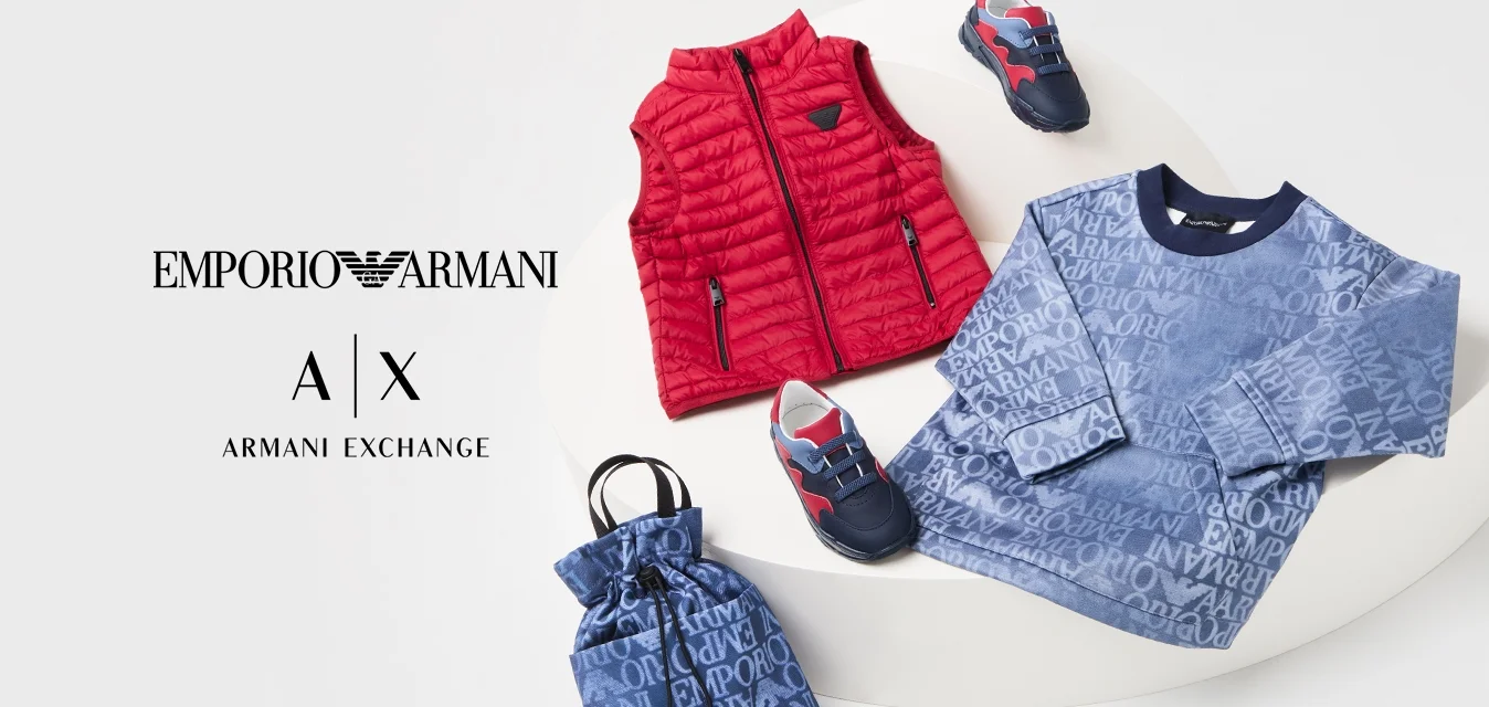 Gilet trapuntato rosso, felpa blu con logo stampato, borsa con coulisse abbinata e sneaker per bambini in blu navy e rosso su una piattaforma bianca.