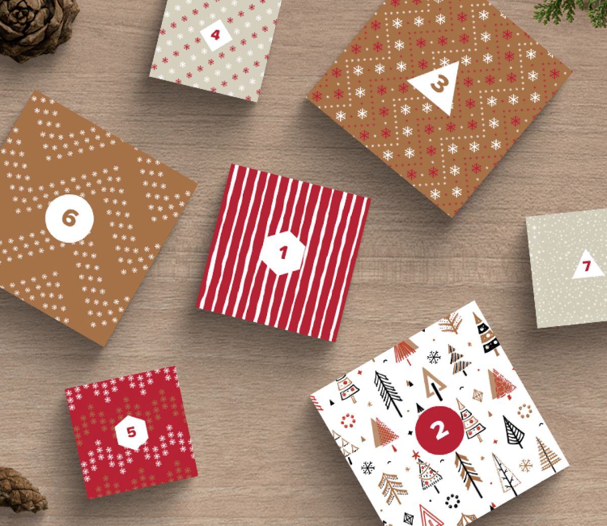 Scatole quadrate a tema natalizio con numeri da 1 a 7 e diversi motivi come fiocchi di neve, strisce e alberi, disposte su uno sfondo rustico in legno con pigne.