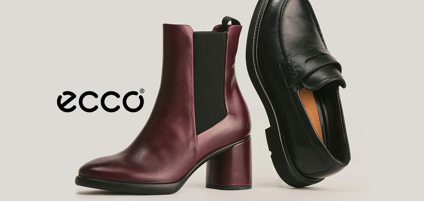 Un anfibio alla caviglia bordeaux con tacco e pannello laterale elastico nero e una mocassino in pelle nera mostrati su uno sfondo chiaro e semplice.