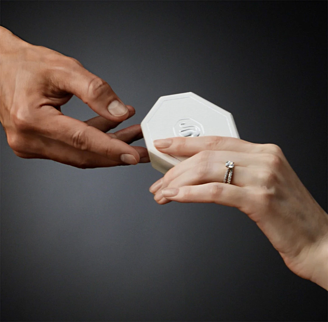 Una mano porge all’altra una confezione regalo Swarovski