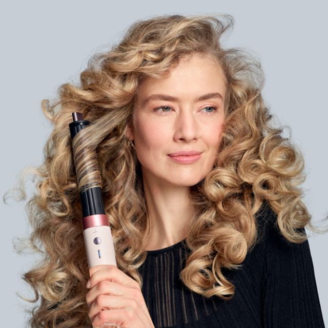 Lo styler asciugacapelli Dyson Airwrap Co-anda2x con cono Co-anda2x da 30 mm usato da una modella bionda per arricciare i capelli.