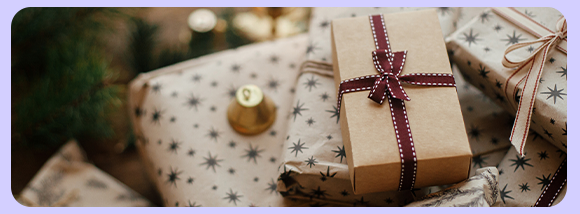 „Foto di pacchi regalo incartati con carta decorata e fiocchi, su sfondo natalizio con albero di Natale fuori fuoco.“ „Foto di pacchi regalo incartati con carta decorata e fiocchi, su sfondo natalizio con albero di Natale fuori fuoco.“