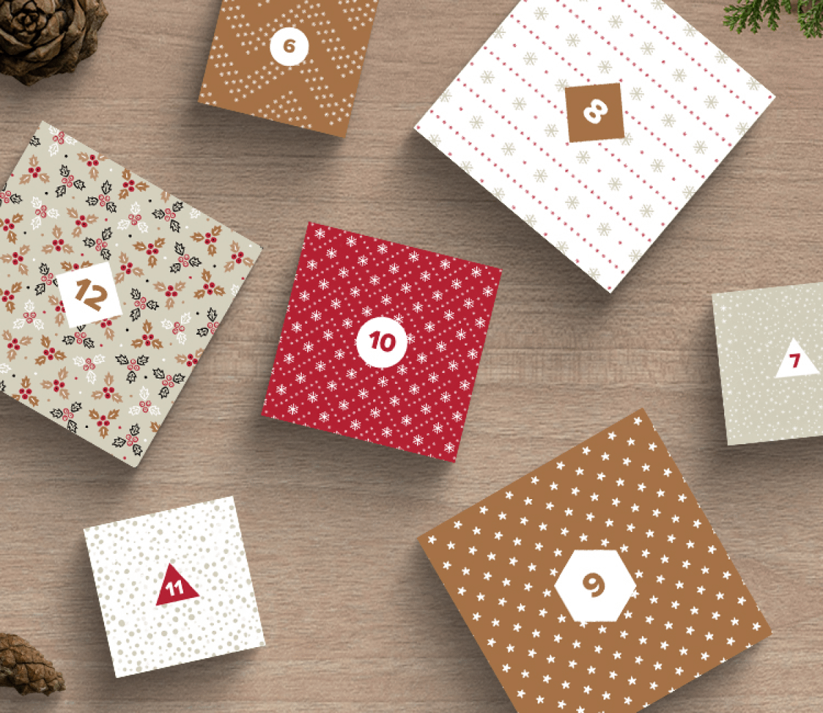 Scatole quadrate a tema natalizio con numeri da 7 a 12 e diversi motivi come fiocchi di neve, strisce e alberi, disposte su uno sfondo rustico in legno con pigne.
