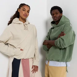 Due felpe con cappuccio si distinguono: una in beige chiaro con tasca frontale e cuciture dettagliate, l'altra in verde tenue con una vestibilità comoda.