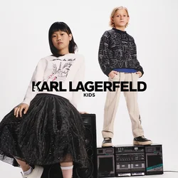 Due bambini sono in piedi su un boombox vintage. Uno indossa una felpa bianca con stampe grafiche e una gonna di tulle nera; l'altro indossa un maglione nero con scritte e pantaloni beige.