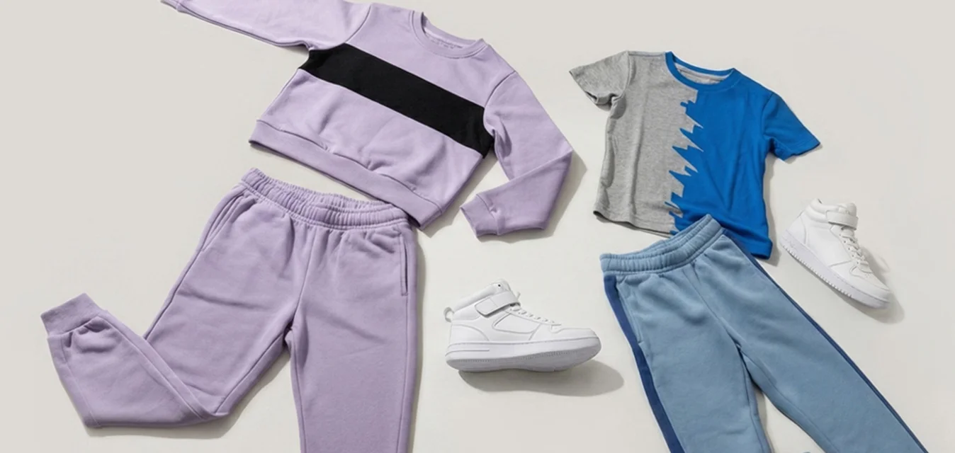 Felpa viola con striscia nera, pantaloni coordinati; camicia blu con accenti grigi, pantaloni blu; sneakers bianche. Tessuto morbido, design casual.