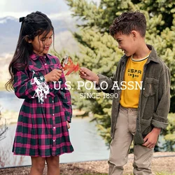 Bambini che giocano all'aperto; ragazza in un vestito scozzese con vita accentuata e stivali marroni; ragazzo in una camicia gialla e giacca di velluto a coste verde con pantaloni beige.