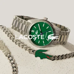 Orologio da polso d'argento con quadrante verde e collana a catena d'argento con emblema di coccodrillo verde su una superficie beige texturizzata.