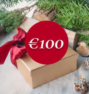 alt="Una confezione regalo avvolta da un fiocco rosso, circondata da sempreverdi. Di fronte c'è la grafica di un cerchio rosso con «100€» all'interno.»
