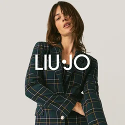 Donna in posa con un blazer a quadri e pantaloni neri con paillettes, su uno sfondo chiaro e uniforme.