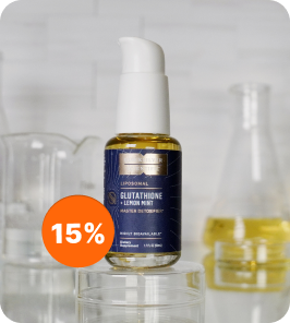 Un flacone a pompa di glutatione liposomiale Quicksilver Scientific su una superficie riflettente, accanto a bicchieri di vetro.