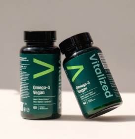 Due flaconi verde scuro di Vitalized Omega-3 Vegan su una superficie di colore neutro.