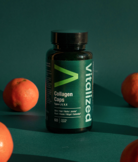 Flacone verde scuro di Vitalized Collagen Caps su sfondo verde scuro con arance sparse ovunque.