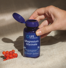 Una bottiglia blu scuro di Life Extension Magnesium Glycinate su un pezzo di tessuto di colore neutro.