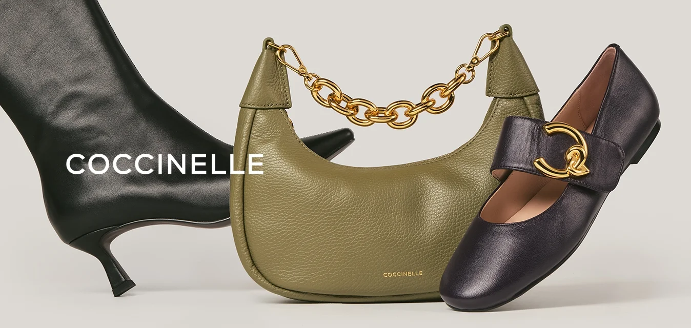 Stivale in pelle nera con tacco medio, borsa verde oliva con manico a catena dorata e scarpa piatta nera con grande fibbia dorata su sfondo beige.