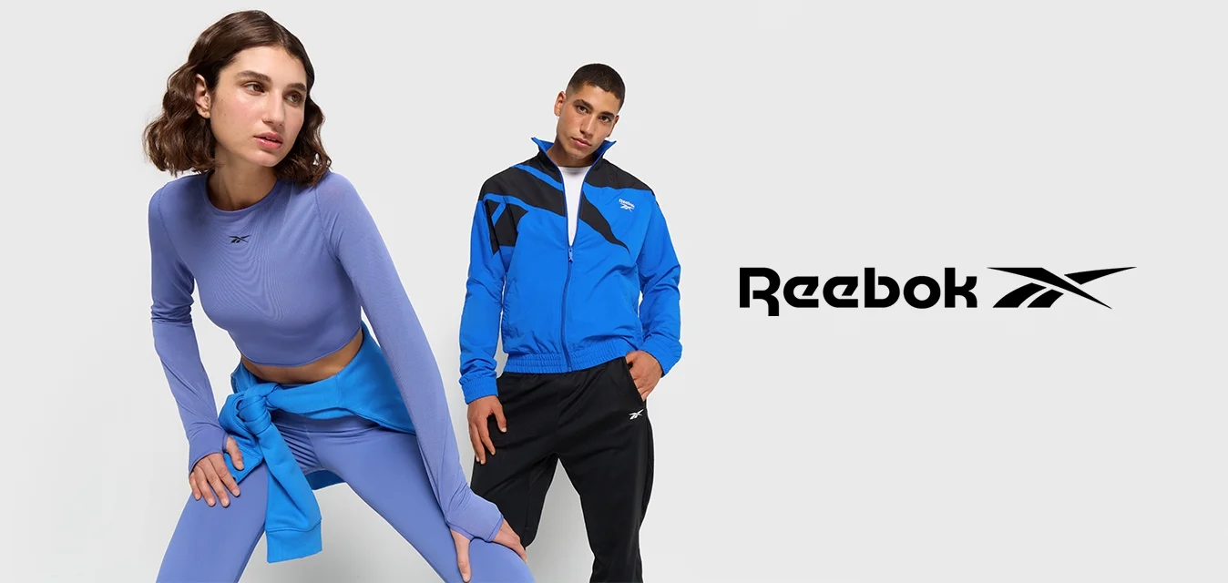 Abbigliamento sportivo con una maglietta a maniche lunghe lavanda e leggings blu, insieme a una giacca blu con dettagli neri e pantaloni neri.