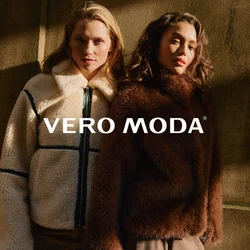 Due donne in piedi vicine, indossano giacche invernali testurizzate: una crema con dettagli neri, l'altra marrone scuro, davanti a un muro in ombra.