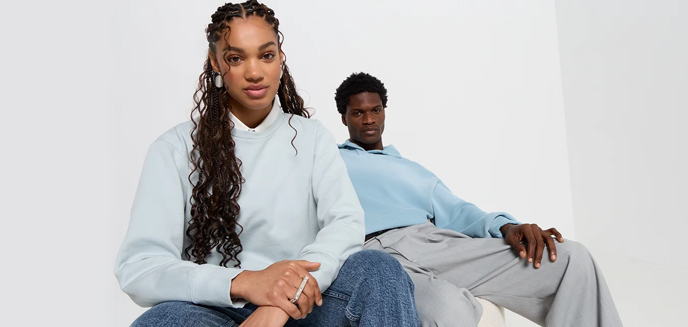 Felpe azzurre su due persone, una con un colletto alto, l'altra con un cappuccio. Jeans scuri su una; pantaloni grigi chiari sull'altra.