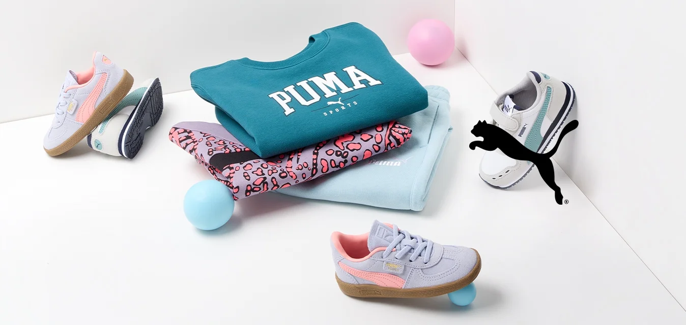 Felpa Puma in teal, leggings stampati in rosa e nero, e tre paia di scarpe da ginnastica in vari colori, sparse con palloni colorati.