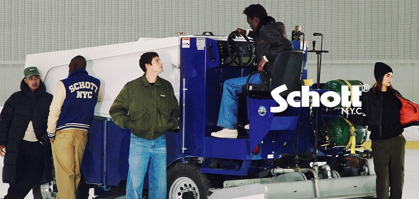 Una macchina da resurfacing del ghiaccio blu con una parte superiore bianca, dotata di un sedile per il conducente, doppi serbatoi di gas verdi e una lama anteriore su un campo di ghiaccio.