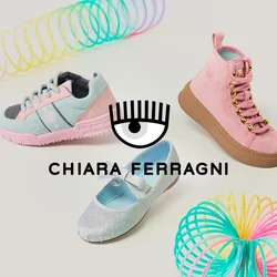 Tre paia di scarpe per bambini (una sneaker rosa, una scarpa argentata con glitter, una sneaker alta rosa) e due colorati giocattoli a spirale di plastica su sfondo chiaro.