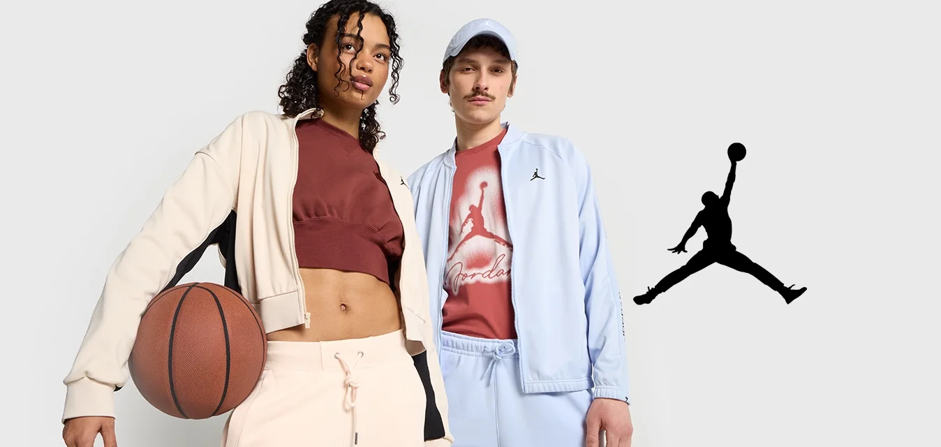 Due persone stanno insieme, una delle quali tiene una pallacanestro. Indossano abbigliamento sportivo: una giacca accorciata beige e nera, un top corto color ruggine e una giacca blu chiaro abbinata a pantaloni dello stesso colore.