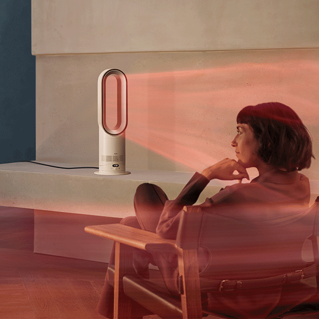 Una donna seduta davanti al termoventilatore Dyson Hot+Cool HF1 Remote Link Pre-heat in modalità riscaldamento.