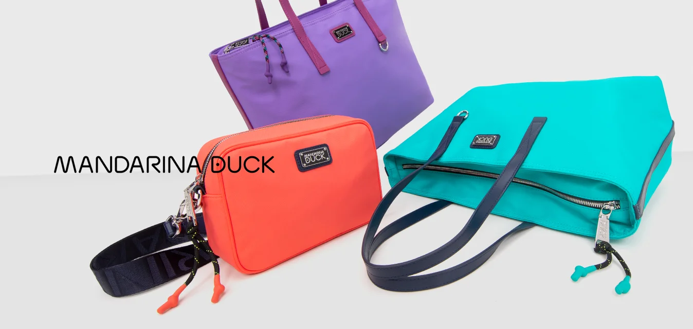 Tre borse colorate – una borsa a spalla viola, una borsa a tracolla corallo e una borsa a mano turchese – disposte su una superficie bianca con ombre minime.