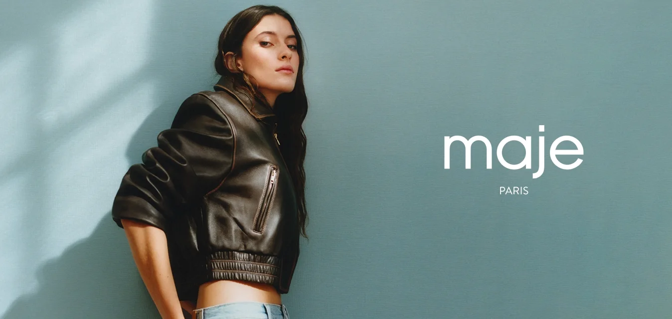 Giubbotto bomber in pelle nera con polsini a coste e tasca zip, abbinato a jeans larghi azzurri con un design a blocchi di colore.