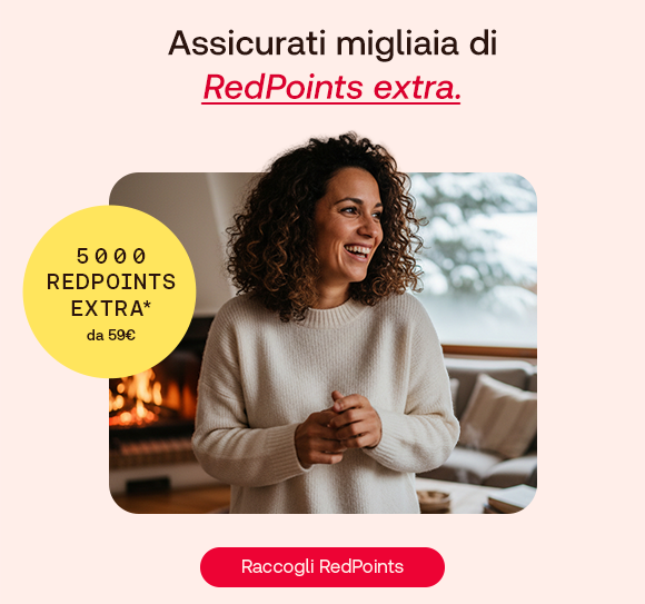Una donna sorridente con un maglione bianco si trova in un ambiente accogliente, con camino acceso e paesaggio innevato fuori dalla finestra. A sinistra, un bollino giallo evidenzia: &ldquo;5.000 RedPoints extra* da 49 &euro;&rdquo;. Sopra, il testo: &ldquo;Assicurati migliaia di RedPoints extra&rdquo;, con &ldquo;RedPoints extra&rdquo; evidenziato in rosso corsivo e sottolineato. In basso, pulsante rosso: &ldquo;Raccogli RedPoints
