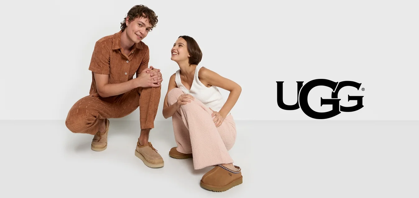 Due modeli posano su uno sfondo neutro. Uno indossa una tuta corta in tessuto marrone; l'altro ha una canotta chiara e pantaloni larghi di un rosa delicato.