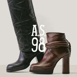 Stivale alto in pelle nera con design strutturato accanto a uno stivaletto con tacco di media altezza in pelle marrone con dettaglio a cinturino avvolgente.