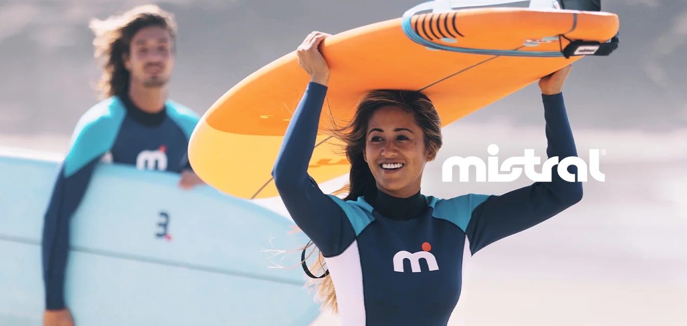 Due surfisti sulla spiaggia; uno tiene una tavola da surf arancione sopra la testa, indossando un costume nero con accenti blu. L'altro porta una tavola di colore azzurro chiaro.
