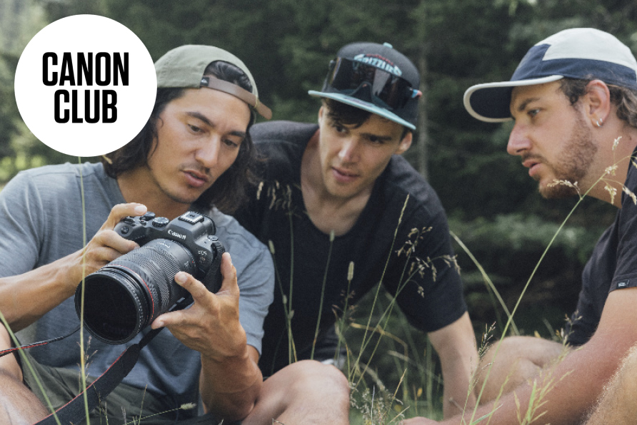 Tre uomini che guardano nel mirino di una fotocamera Canon