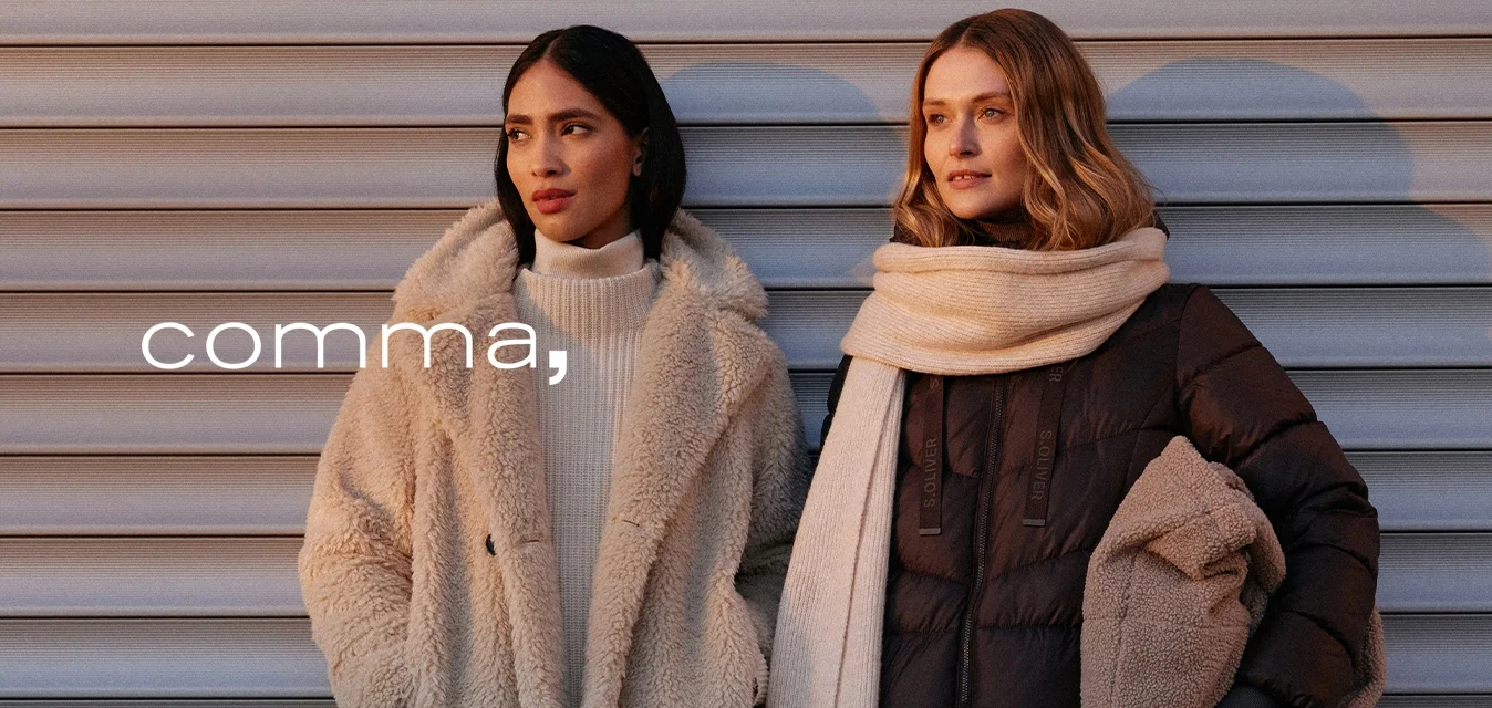 Due donne stanno una accanto all'altra, una indossa un cappotto beige peloso e l'altra una giacca imbottita scura abbinata a una sciarpa chiara.