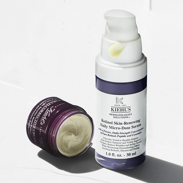 Flacone di Retinol Skin-Renewing Daily Micro-Dose Serum accanto a un vasetto aperto di crema viso Kiehl&rsquo;s, su fondo bianco con luce naturale.