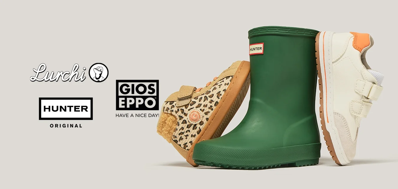 Tre scarpe per bambini: una sneaker leopardata con lacci arancioni, uno stivaletto di gomma verde per la pioggia e una sneaker bianca con tallone arancione e cinturini in velcro.