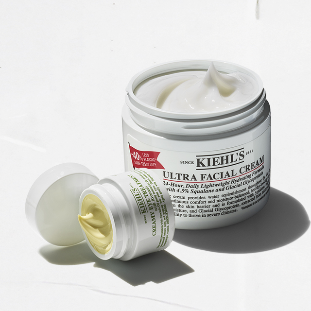 Vasetto aperto di Ultra Facial Cream di Kiehl&rsquo;s accanto a un contorno occhi in formato compatto, entrambi su fondo bianco.