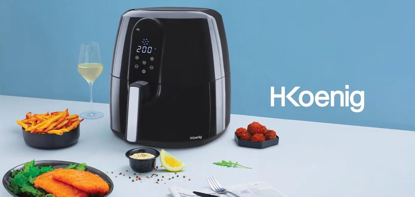 Friggitrice ad aria nera con display digitale, dettagli argentati, accanto a piatti di patatine croccanti, pesce e un bicchiere di vino bianco su una superficie chiara.