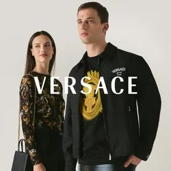 Un uomo e una donna stanno uno accanto all'altra, indossando abiti con motivi neri e dorati; la donna tiene una borsa nera con una tracolla a catena dorata.