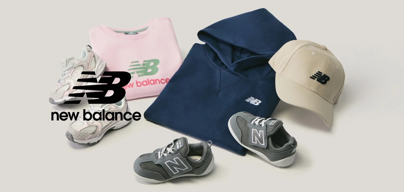 Felpa rosa piegata, felpa con cappuccio blu navy, cappellino beige, due paia di scarpe da ginnastica grigie disposti su sfondo chiaro.