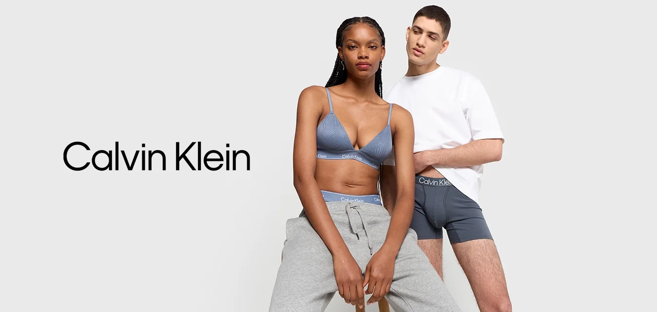 Pantaloni della tuta grigi e un bralette blu con spalline sottili, accompagnati da una maglietta bianca e boxer grigi, mostrati su uno sfondo chiaro.