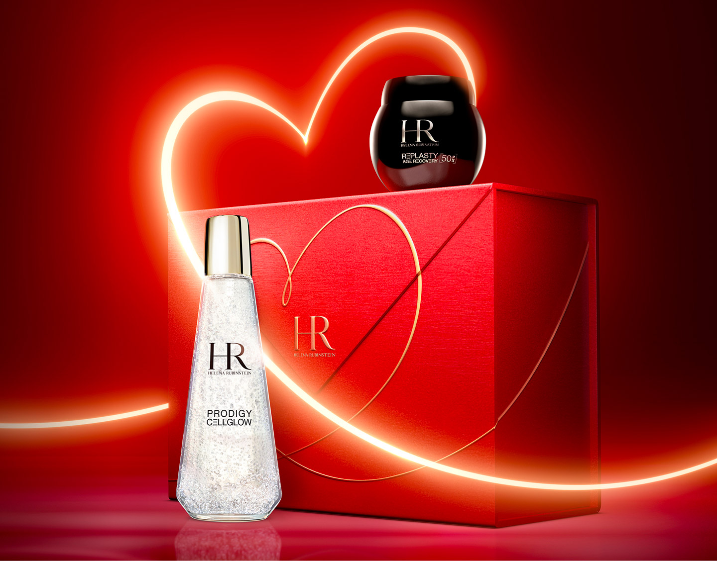 Immagine dei prodotti Age Recovery Night e Dewy Essence con un nastro luminoso a forma di cuore che avvolge una confezione regalo rossa con un disegno a cuore simile