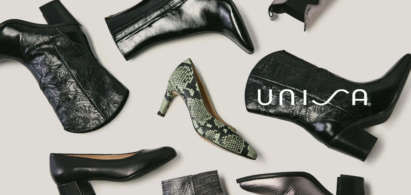 Varie scarpe con tacco e stivali da donna disposti su uno sfondo chiaro, comprendenti modelli in pelle nera, stampa serpente e lavorazione grigia.