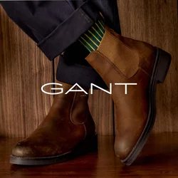 Stivali Chelsea in pelle marrone con pannelli elastici laterali, suola in gomma nera e texture liscia, abbinati a calzini a righe verdi.